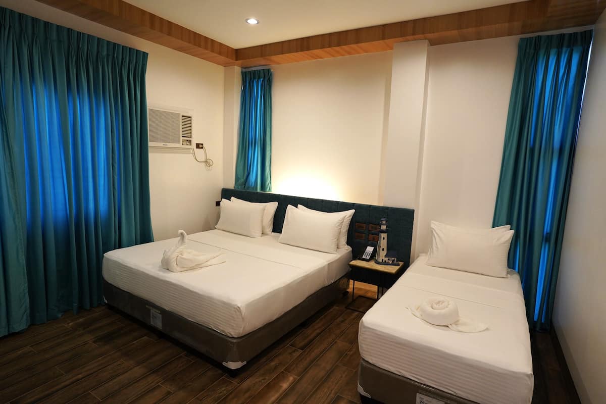 A hotel room with two beds, a nightstand, a telephone, and a wall-mounted air conditioning unit.