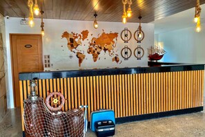 Un comptoir d’accueil agrémenté d’une carte du monde, d’un gouvernail de bateau et d’un mur fait de lattes de bois.