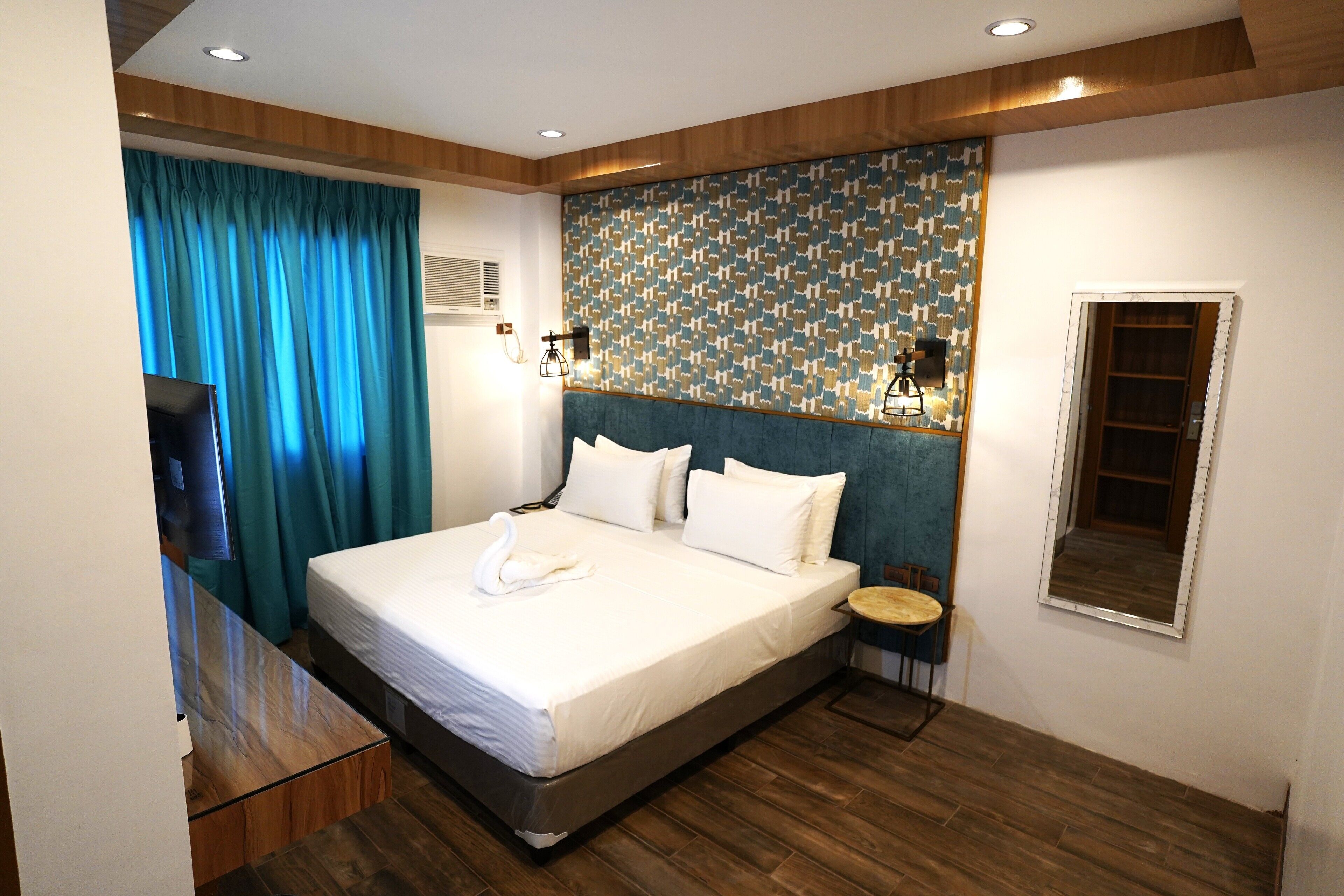 Een moderne hotelkamer met een groot bed, een klein rond tafeltje en een spiegel aan de muur.