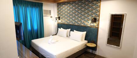 Une chambre d’hôtel moderne avec un grand lit, une petite table ronde et un miroir fixé au mur.