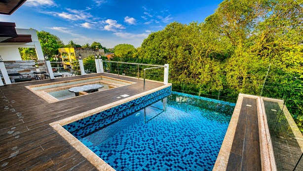 A rooftop swimming pool with a tiled floor, surrounded by a wooden deck and metal railings. - Lighthouse Point Hotel (Dumaguete)
