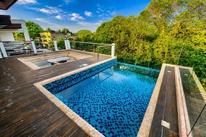 A rooftop swimming pool with a tiled floor, surrounded by a wooden deck and metal railings. - Lighthouse Point Hotel (Dumaguete)