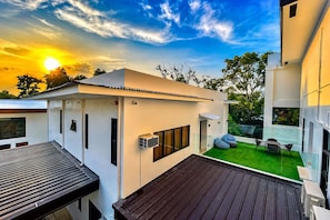 A modern building with a flat roof, a small outdoor seating area with cushions, and a clear view of the sky. - Lighthouse Point Hotel (Dumaguete)