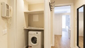 A laundry room with a washing machine, a telephone, and a small shelf. - S.Maria Valle Apartment 3 (Milano)