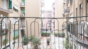 A courtyard with a metal railing, potted plants, and multi-story buildings in the background. - S.Maria Valle Apartment 3 (Milano)