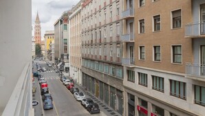 A multi-story building with balconies, a street view, and a distant tower. - Missori Apartment 2  (Milano)