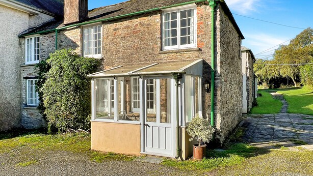 A traditional stone house with a conservatory, a chimney, and a garden pathway. - Orchard Cottage, Brayford (Brayford)