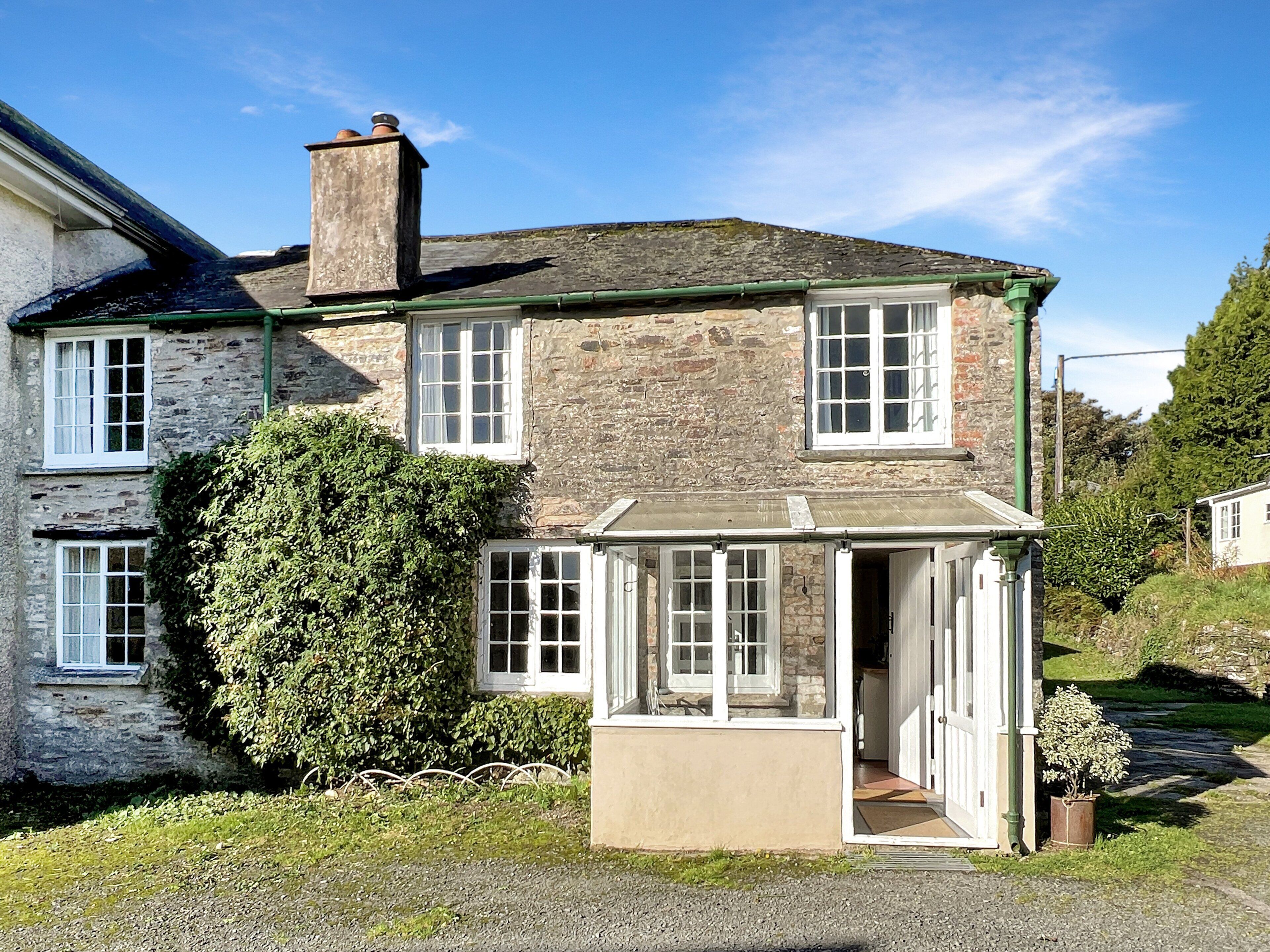 A stone house with a chimney, a covered porch, and a garden.