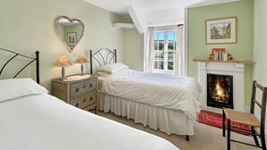 A bedroom with a bed, dresser, mirror, and fireplace. - Orchard Cottage, Brayford (Brayford)