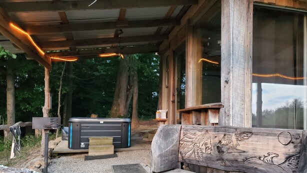 Een rustieke hut met een houten bank, een grote verwarming en een raam met lichtjes.