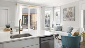 A modern kitchen with a white countertop, stainless steel sink, and a dishwasher.
