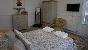 A bedroom with a bed, a dresser, a chair, a mirror, and a television. - Lovely, spacious apartment - sleeps 5 (Ryde)