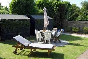 Eine Terrasse mit Tisch, Stühlen und Liege.