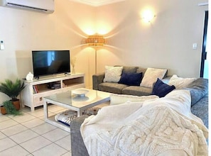 Ein Wohnzimmer mit einer Couch, einem Fernseher und einer Lampe.