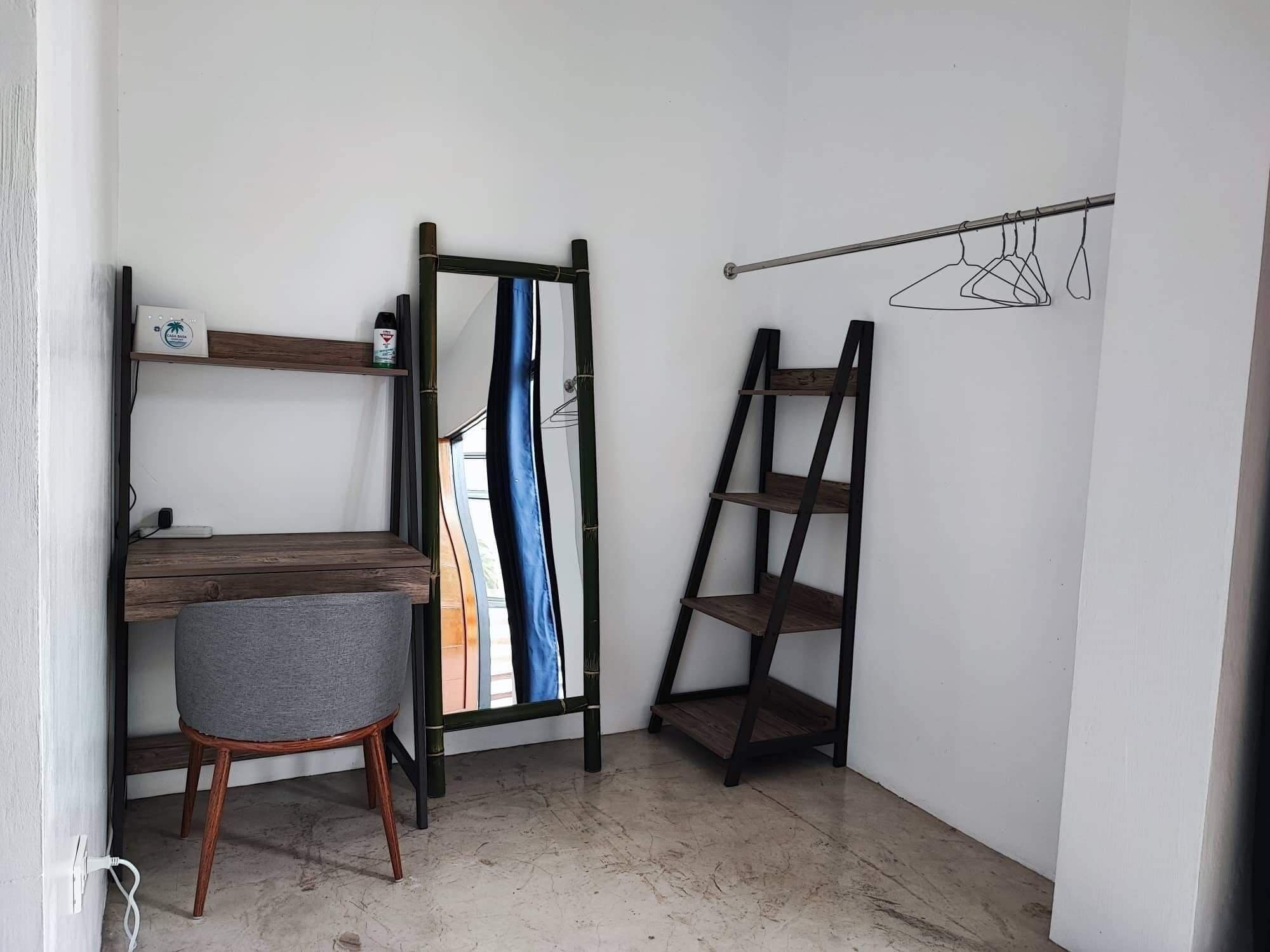 A corner room with a desk, chair, and two shelves.