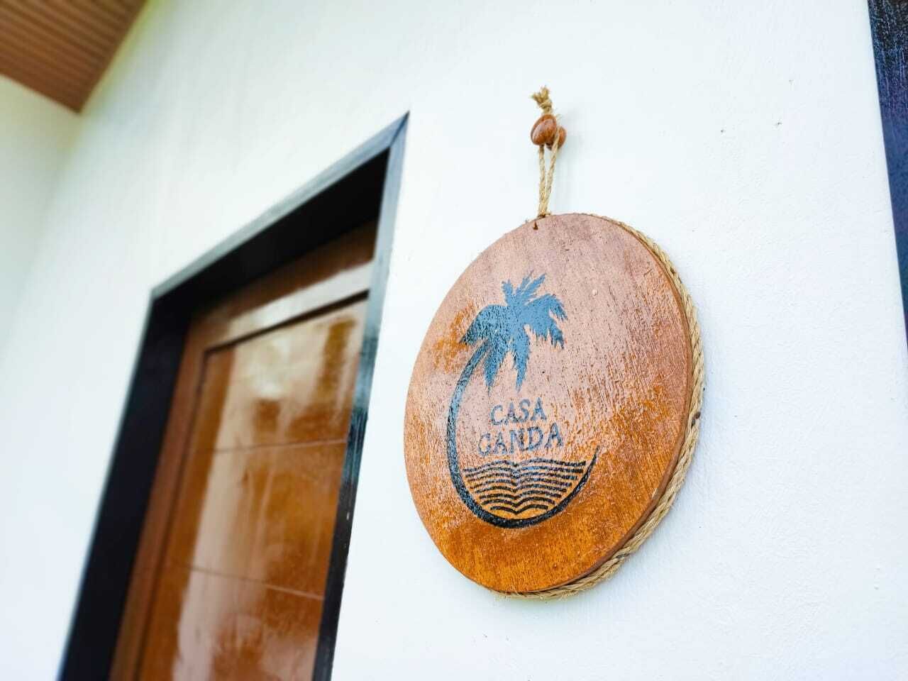 A wooden plaque with a palm tree and waves, hanging on a white wall next to a wooden door.