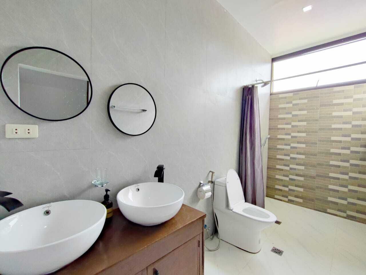 A modern bathroom with two large white sinks, a toilet, and a shower.
