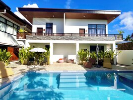 Una casa moderna de dos pisos con una piscina al frente.