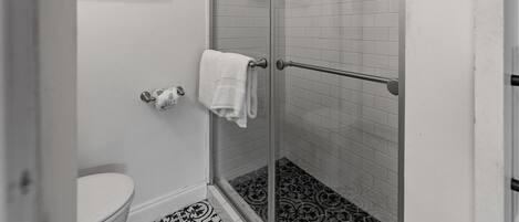 Ein Badezimmer mit Duschkabine, Toilette und Handtuchhalter.