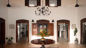 A spacious room with a round table, a chandelier, and wooden doors with decorative glass panels. - Quintessential colonial villa with pool and full staff (Habaraduwa)