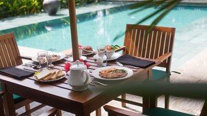 A dining table set for breakfast with a view of a swimming pool. - Quintessential colonial villa with pool and full staff (Habaraduwa)