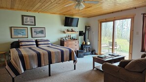 Una habitación acogedora con cama, televisión, chimenea y un ventanal grande.