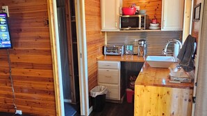 Eine kleine Küche mit Holzwänden, einer integrierten Mikrowelle und einem Spülbecken.