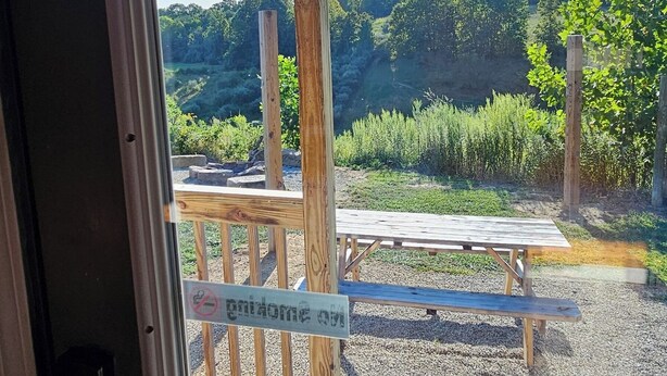 Eine Holterrasse mit Picknicktisch und Bänken, mit Blick auf ein bewaldetes Gebiet.