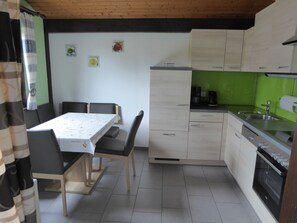 Une cuisine équipée d’une table à manger, de chaises, de placards, d’un évier et d’une cuisinière.