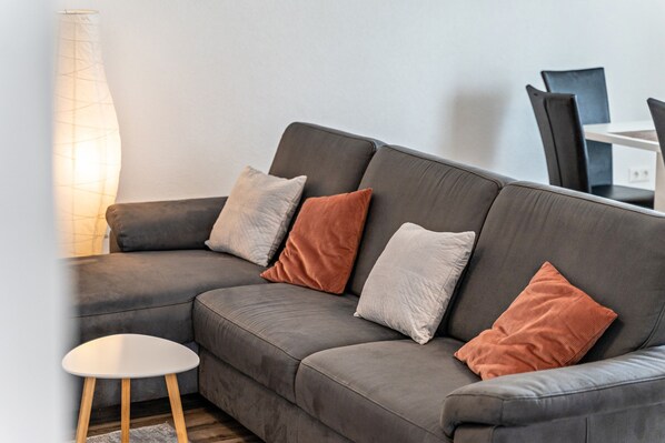 Un salon moderne avec un canapé gris, une petite table ronde et un grand lampadaire.