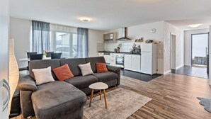 A modern living room with a grey sofa, a small table, and a kitchen in the background. - Apartment 'Familie Richter' with Wi-Fi (Lahr)