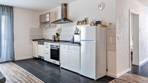 A modern kitchen with white cabinets, a stainless steel range hood, a built-in oven, and a refrigerator. - Apartment 'Familie Richter' with Wi-Fi (Lahr)