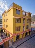 A multi-story yellow building with balconies and a stone-paved ground.
