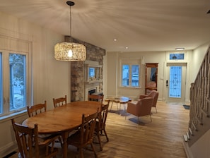 Un vaste espace dédié à la salle à manger, avec une table et des chaises en bois, une cheminée en pierre et un luminaire suspendu.