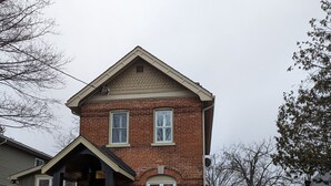 Una casa a due piani in mattoni con un portico, un garage e una strada privata.