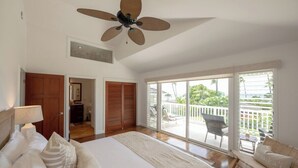 Ein Schlafzimmer mit einem großen Bett, einem Deckenventilator und einem Balkon mit Gartenmöbeln.