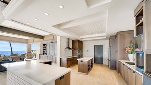 A modern kitchen with a large island, built-in appliances, and a view to the outside.