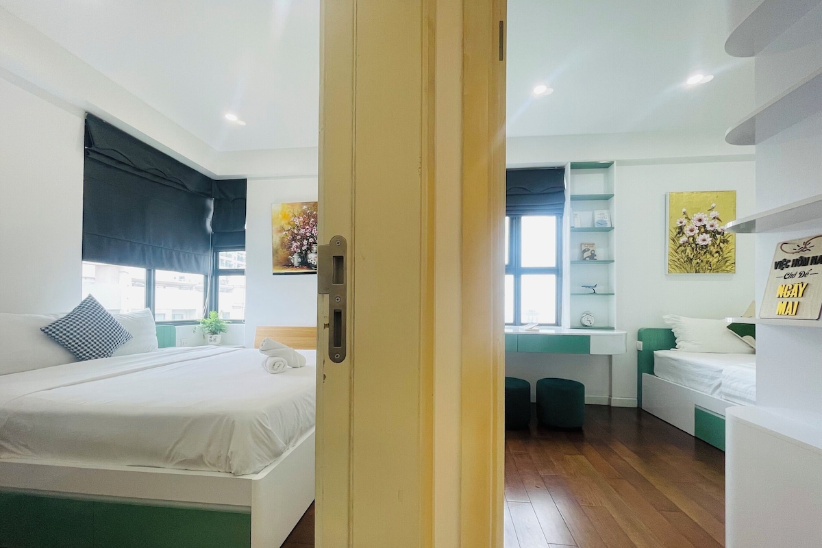 A modern hotel room with a large bed, a desk, and a small seating area.