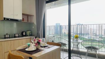 A modern kitchen with a dining area, a balcony with a view of the city, and a table set for two.