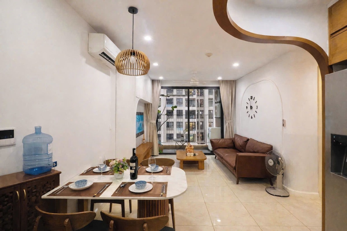 A modern living room with a brown sofa, dining table with chairs, and a large water dispenser.