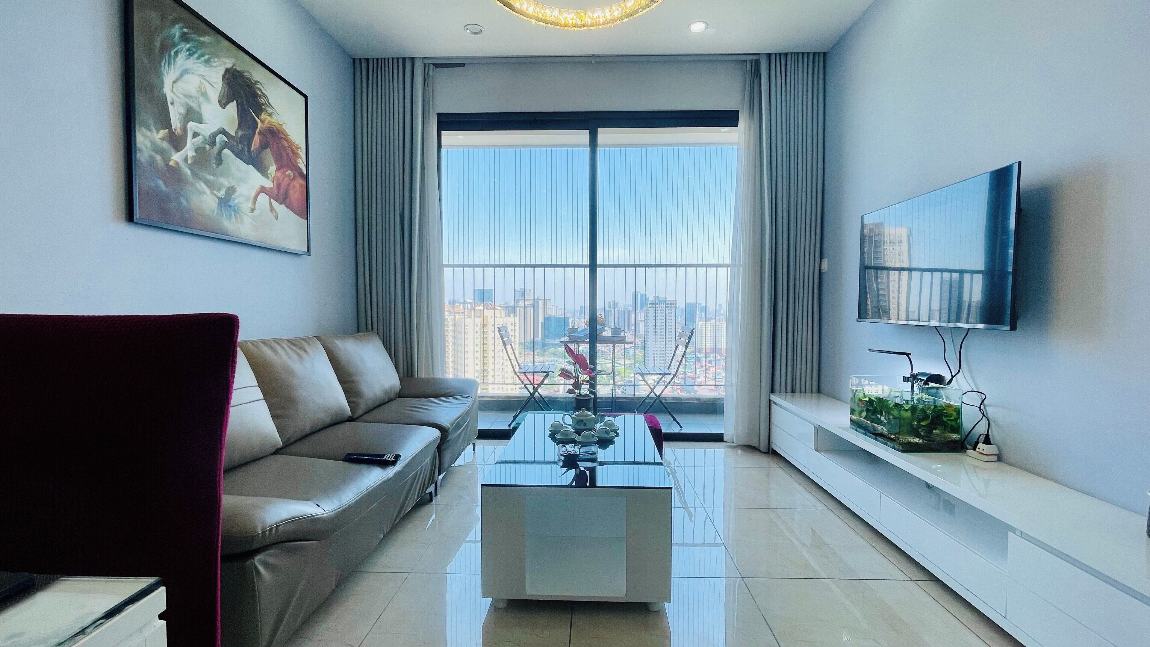 Una sala moderna con un sofá, una mesa de centro, un televisor y un balcón con vistas a la ciudad.