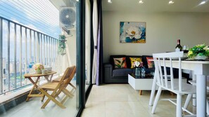 Una sala de estar moderna con comedor, un sofá con cojines de colores, un cuadro en la pared y un balcón con vistas a la ciudad.