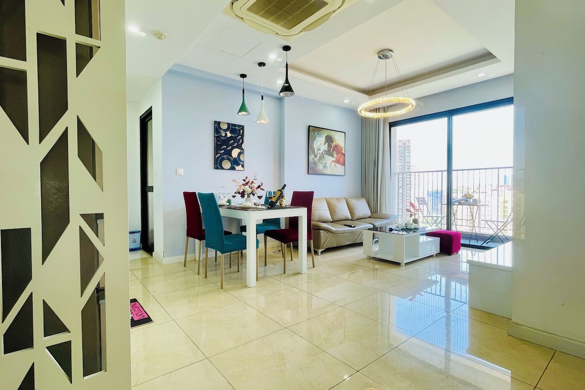 A modern living room with a dining area, a sofa, and a balcony with a view.