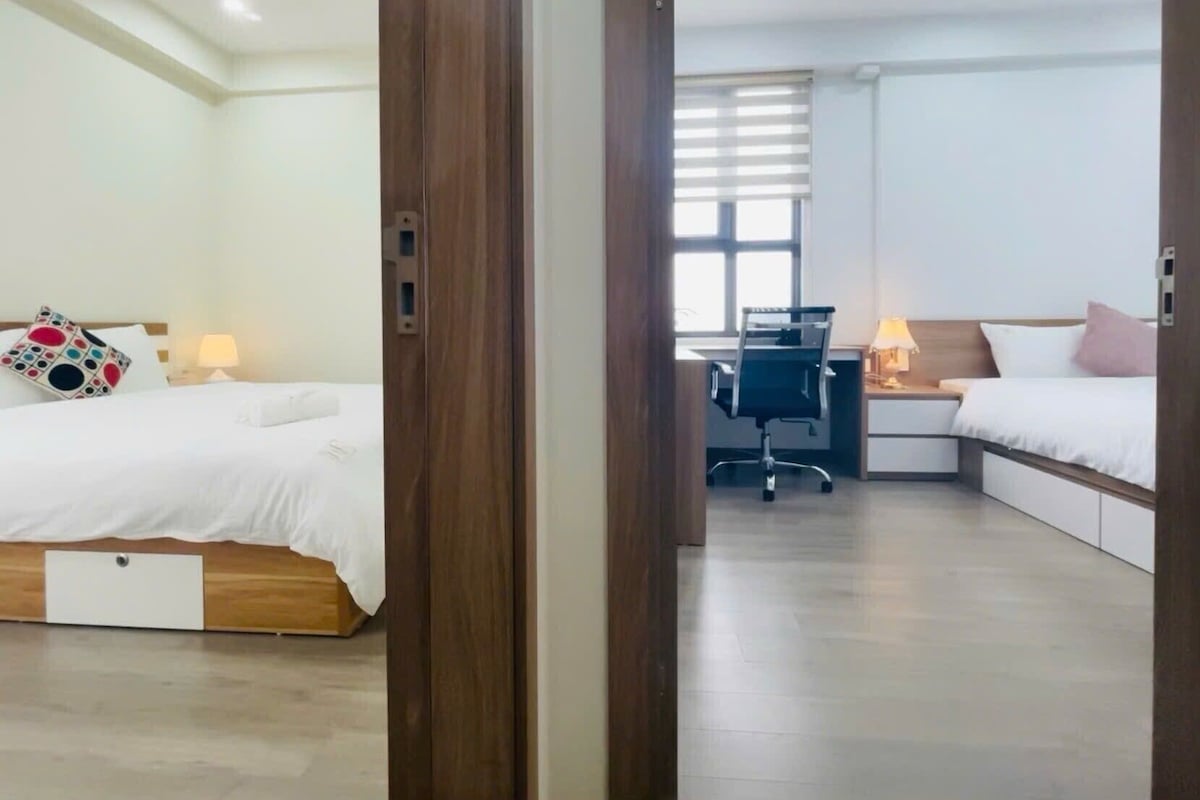 A hotel room with two beds, a desk, and a chair.