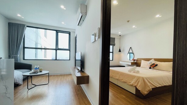 Una camera d'albergo moderna con un'ampia finestra, un divano, un comodino, una televisione e un letto.