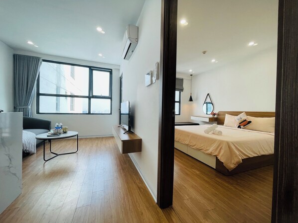A modern hotel room with a large window, a sofa, a bedside table, a TV, and a bed. - Luna's House in Vinhomes D'Capitale (Hanoi)