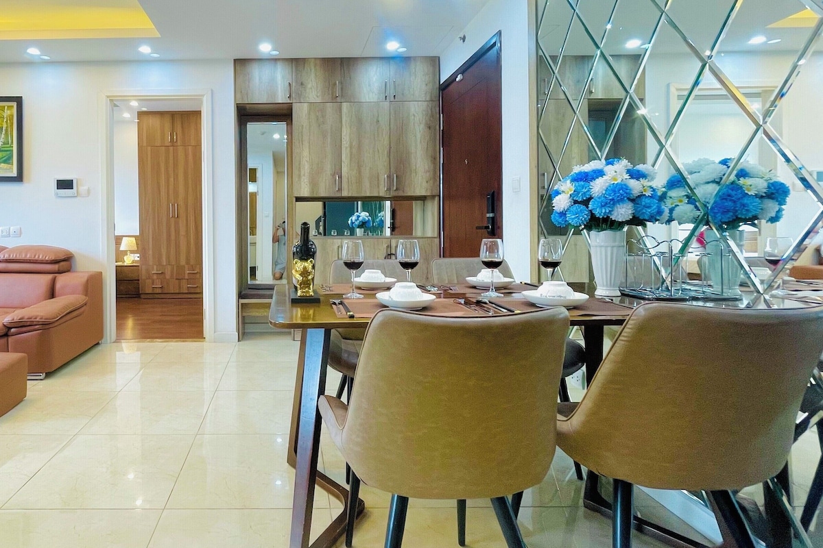 A modern living room with a sofa, coffee table, and dining area with chairs and a table set for a meal.