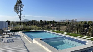 A rectangular swimming pool with a tiled edge, surrounded by a deck with chairs and a small table. - Wine Country Hilltop Home w/Views & Pool & Spa - New Listing! (Temecula)
