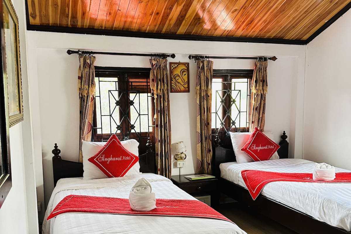 Une chambre d’hôtel avec deux lits, un plancher en bois et un plafond en bois.
