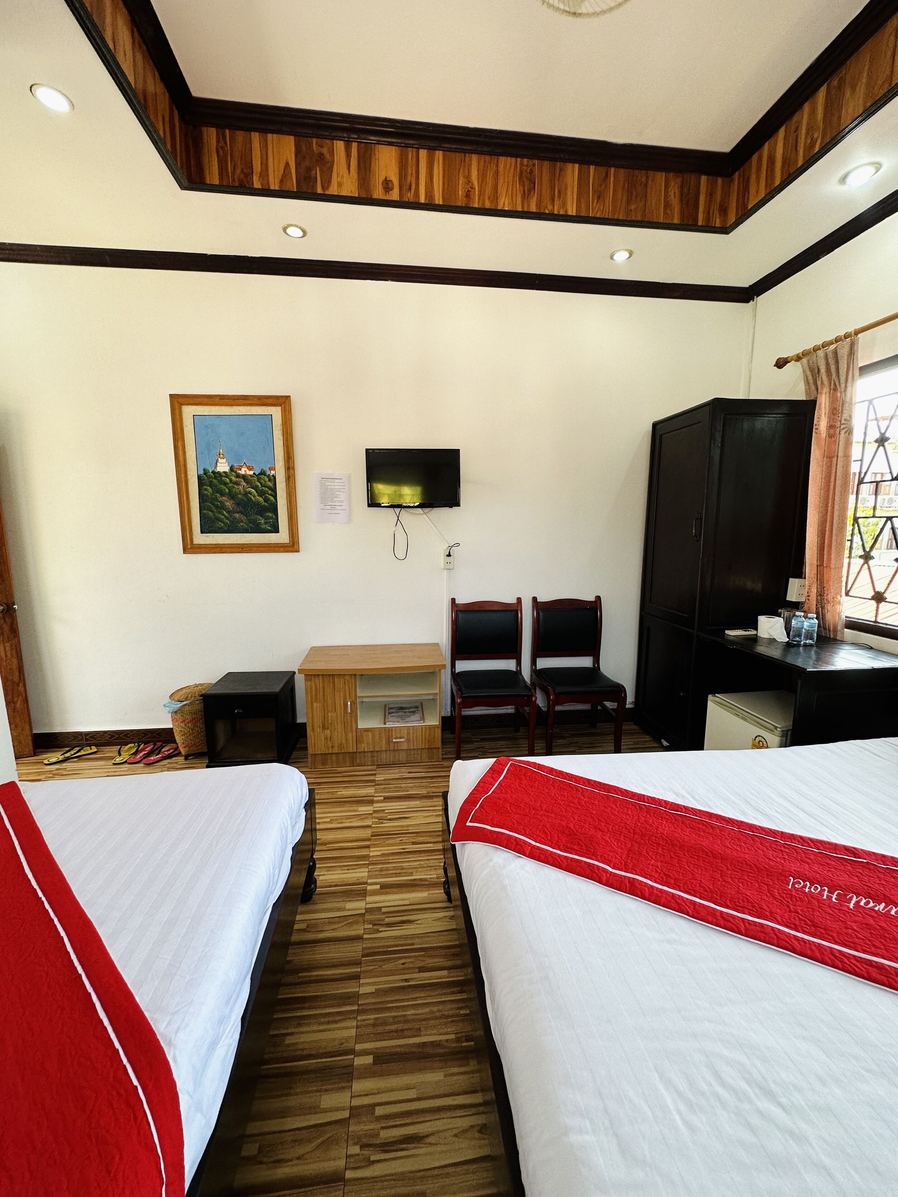 A hotel room with two beds, a desk with a TV, a chair, and a wardrobe.
